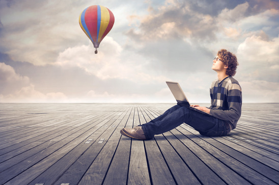 Guy on his laptop sitting on a dock